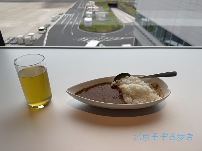 空港ラウンジで提供されているカレーと飲み物、窓の外の景色
