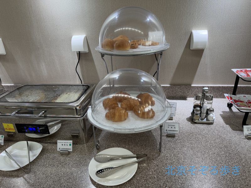 空港ラウンジのビュッフェでドーム型のカバーに入ったパンが並べられている様子